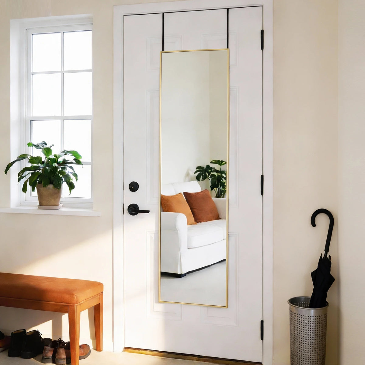 A full-length arched wall mirror with a gold aluminum frame hanging on a white door.