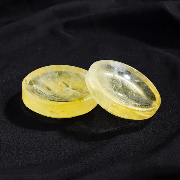 Two polished yellow citrine crystals resting on a dark surface.