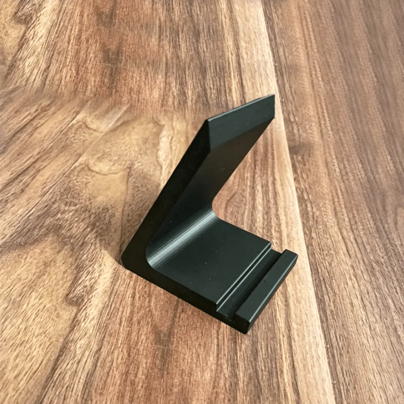 A black minimalist vinyl record and CD display stand positioned on a wooden surface.