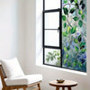 A window with green leaf privacy film showing a vibrant pattern of leaves and branches.