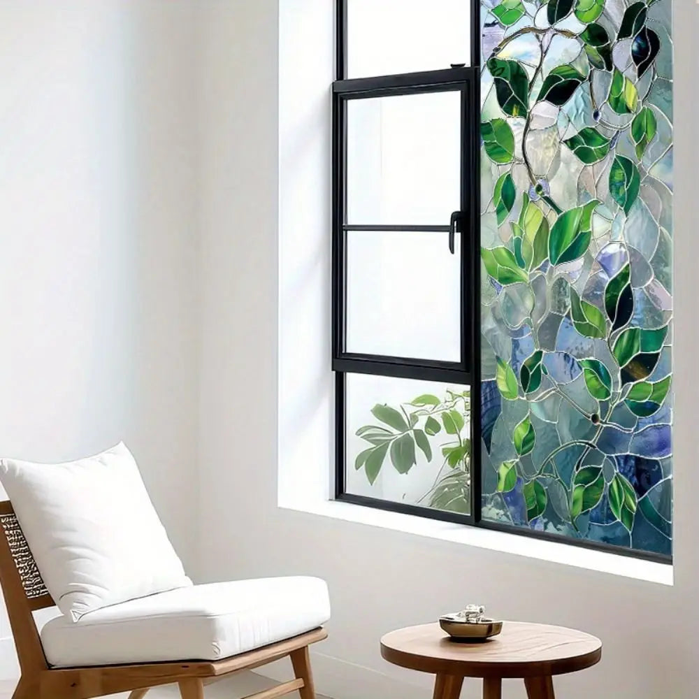 A window with green leaf privacy film showing a vibrant pattern of leaves and branches.