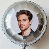 A silver foil balloon shaped like a circle, featuring a portrait of a man.
