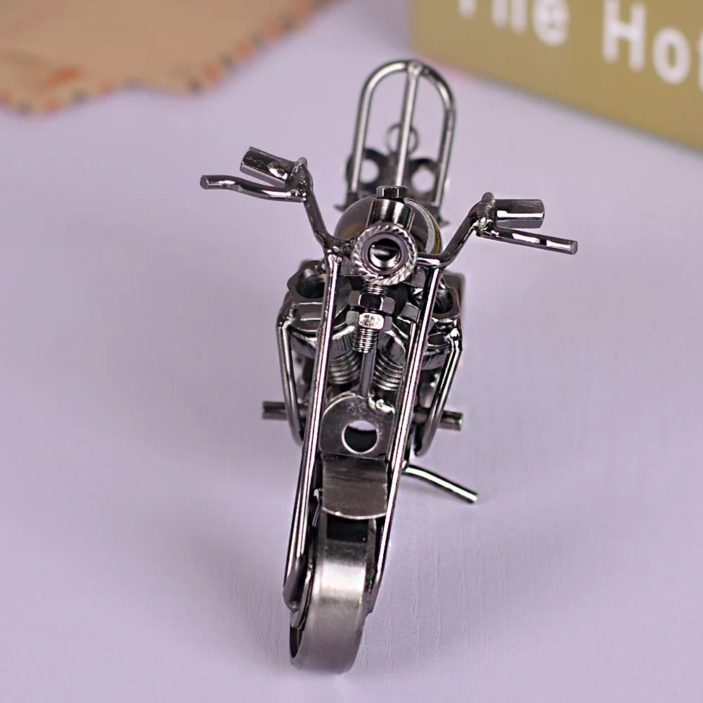 A silver handcrafted metal motorcycle model with detailed engine components and handlebars displayed on a white surface.