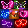 Various neon butterfly and heart signs in pink, green, blue, and red colors displayed on a surface.