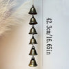 A vertical arrangement of bronze metal wind chimes hanging from a thin cord against a white background.