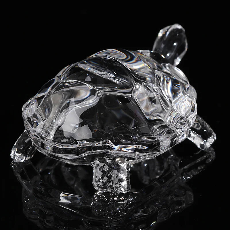 Clear glass miniature tortoise statue reflecting on a dark surface.