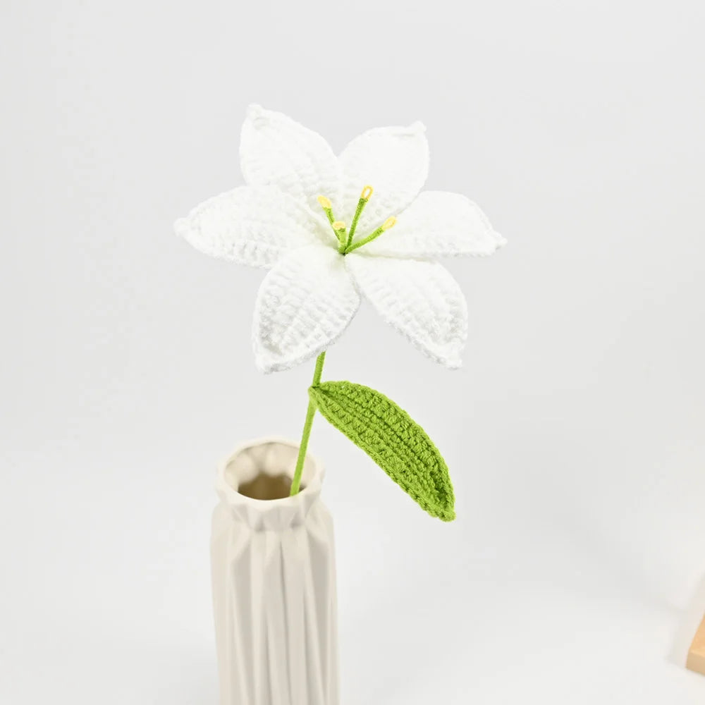 A hand-crocheted white lily flower with a green stem displayed in a vase.