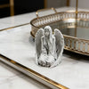 Estatua de ángel plateada con alas sobre una superficie de mármol junto a una bandeja con borde dorado.