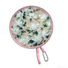 A pink, round, portable foldable cooling handheld fan with a floral pattern.