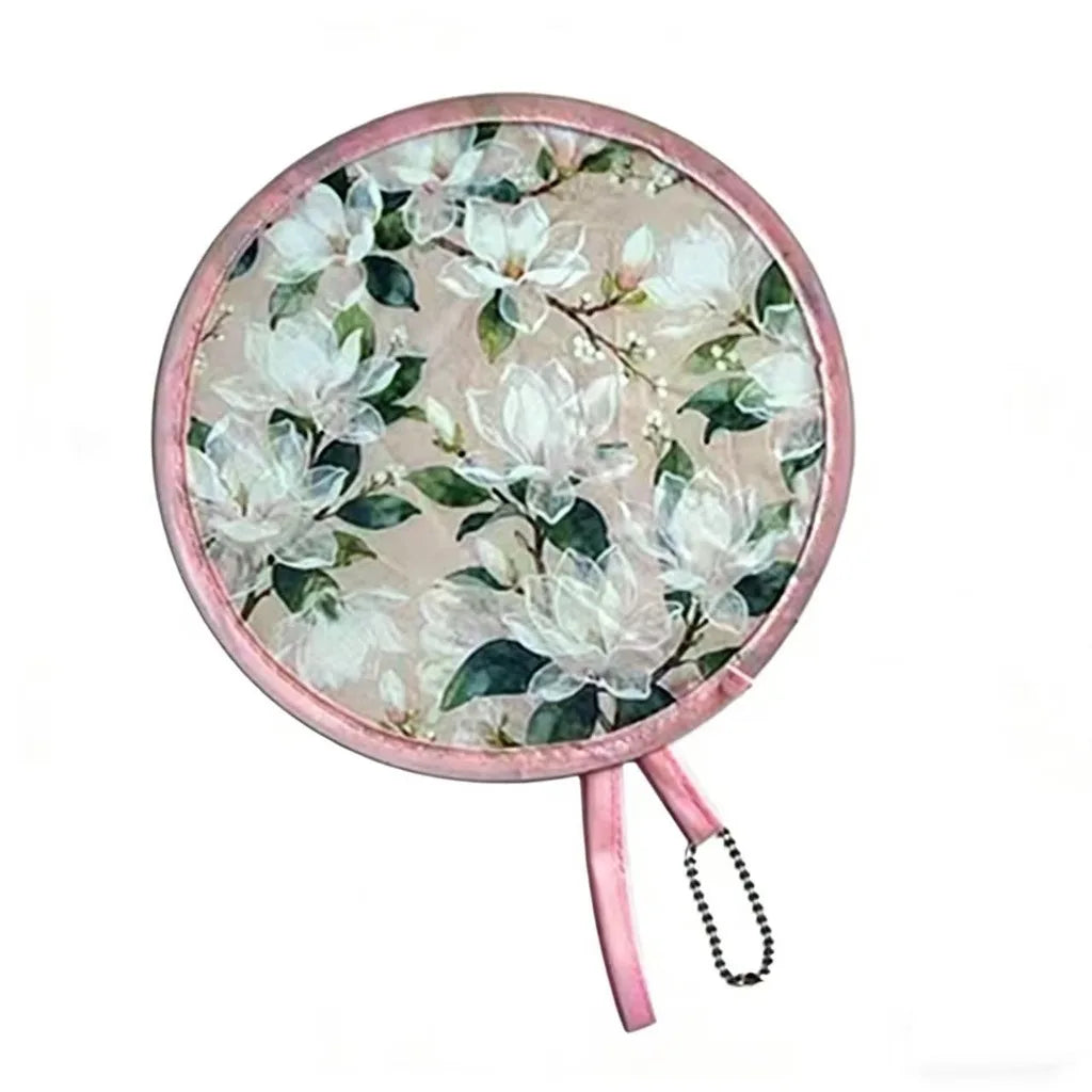 A pink, round, portable foldable cooling handheld fan with a floral pattern.