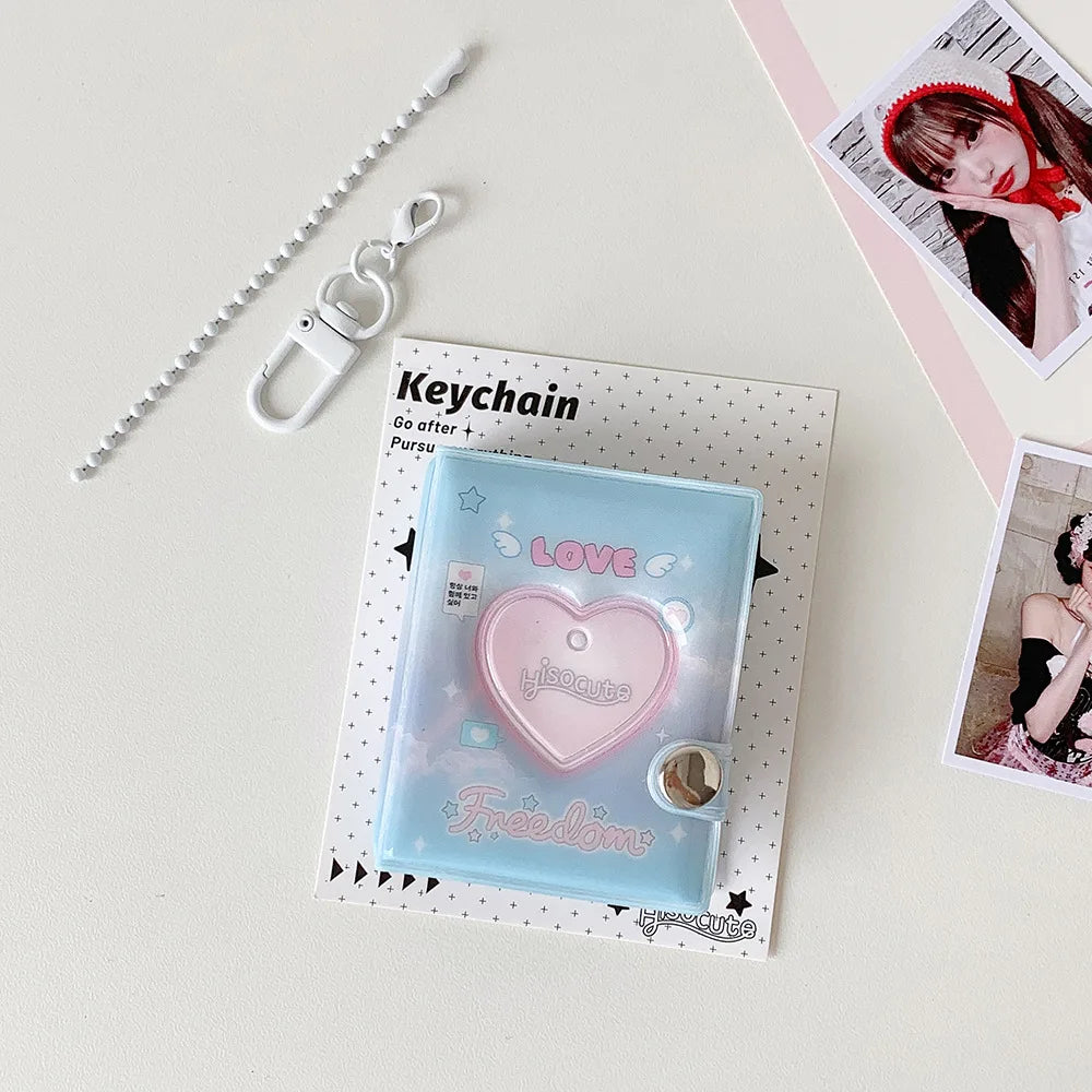 A clear blue photo album with a pink heart design and a silver keychain attached to a beaded chain.