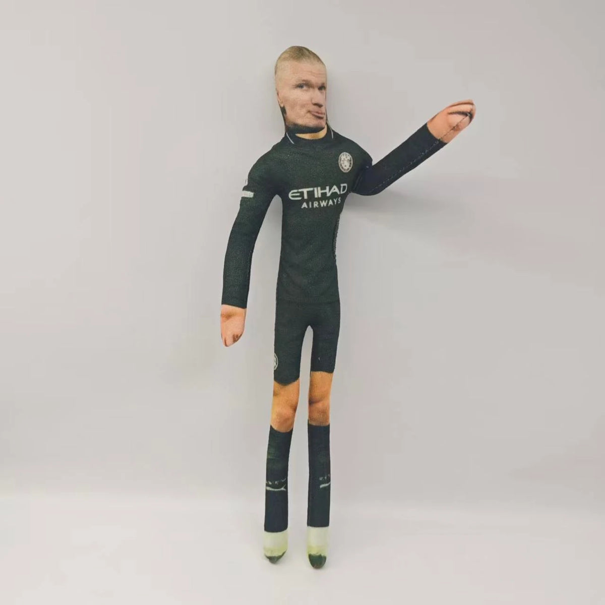 Figura masculina en uniforme de fútbol verde oscuro posando contra un fondo gris claro.