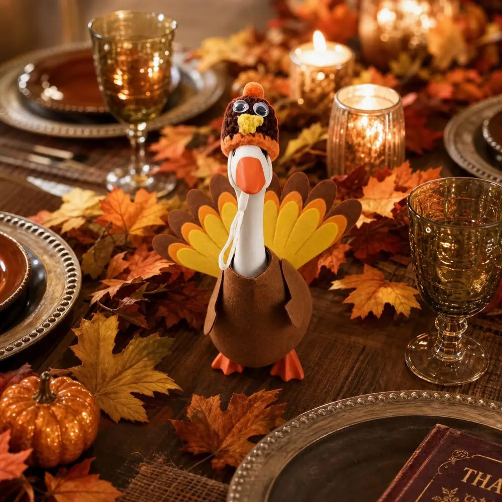 A felt turkey costume resembling a goose statue is displayed among autumn leaves and gold-toned glassware.