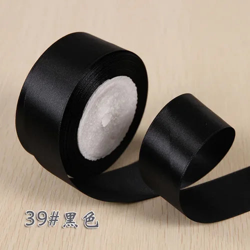 A roll of black silk satin ribbon used for gift wrapping and craft projects.