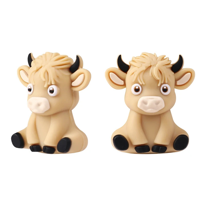 A pair of light beige silicone goat figurines with black accents for jewelry making and DIY crafts