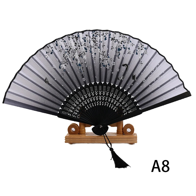 Black lace folding hand fan with silver accents displayed on a wooden stand.