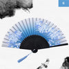 A vintage silk bamboo folding hand fan with blue and white painted designs against a white background.