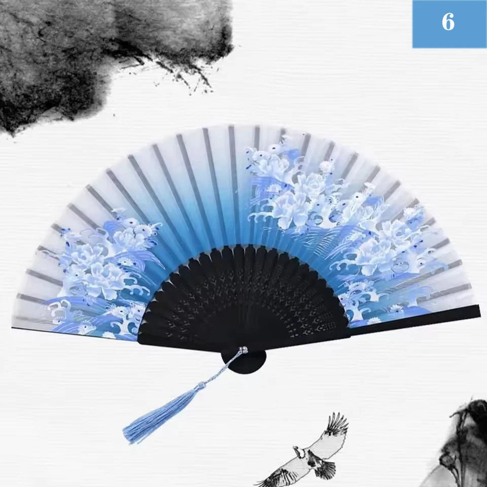A vintage silk bamboo folding hand fan with blue and white painted designs against a white background.