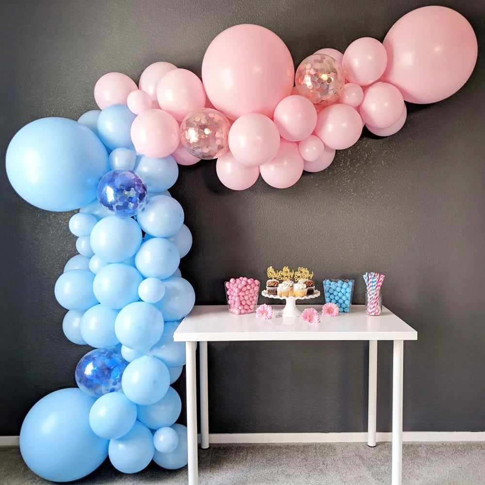 A balloon arch display featuring pastel blue, pink, and purple latex balloons on a white table.
