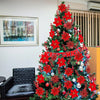 A brightly decorated Christmas tree adorned with red artificial flowers and ornaments.