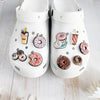 A pair of white Doughnut Shoe Charms for Crocs and slides displayed on a light wooden surface.