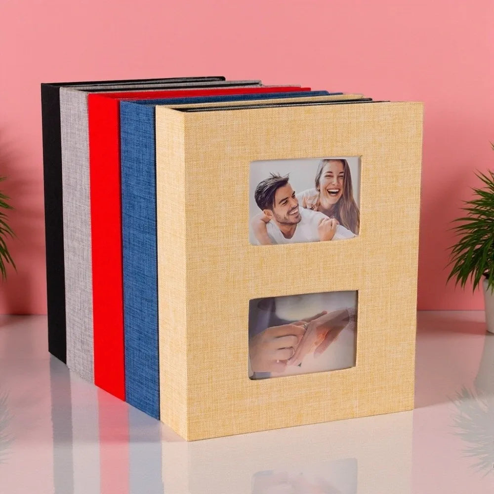 A stack of linen-cover photo albums in various colors, including red, blue, and yellow, with a square window displaying a pho