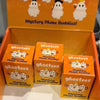 An orange box containing ghost phone buddy decorations and several individual ghost phone buddy charms.