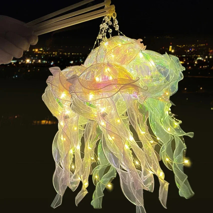 A handmade jellyfish lantern made of translucent, glowing fabric is being held by chopsticks against a dark night sky backdro