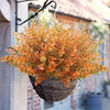 A bouquet of artificial orange and yellow fall flowers in a woven basket hanging on a wooden structure.