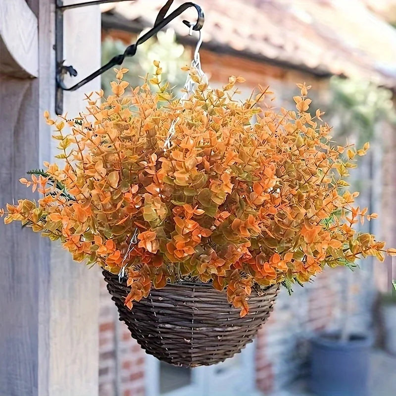 A bouquet of artificial orange and yellow fall flowers in a woven basket hanging on a wooden structure.