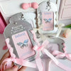 A hand holds a silver lace PU card holder with a pink ribbon bow keychain and matching butterfly charm.