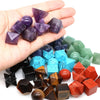 A hand holds a set of seven purple and reddish-orange platonic geometry healing crystals for meditation.