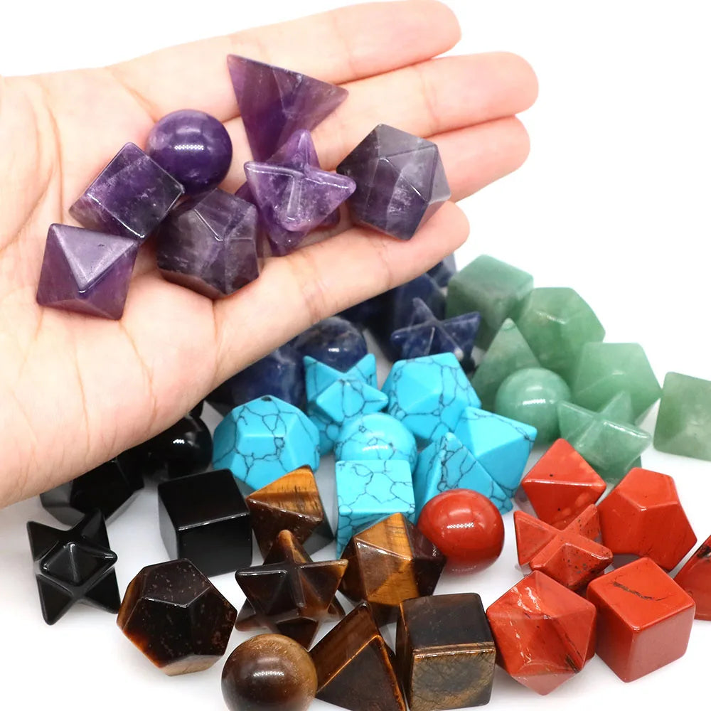 A hand holds a set of seven purple and reddish-orange platonic geometry healing crystals for meditation.