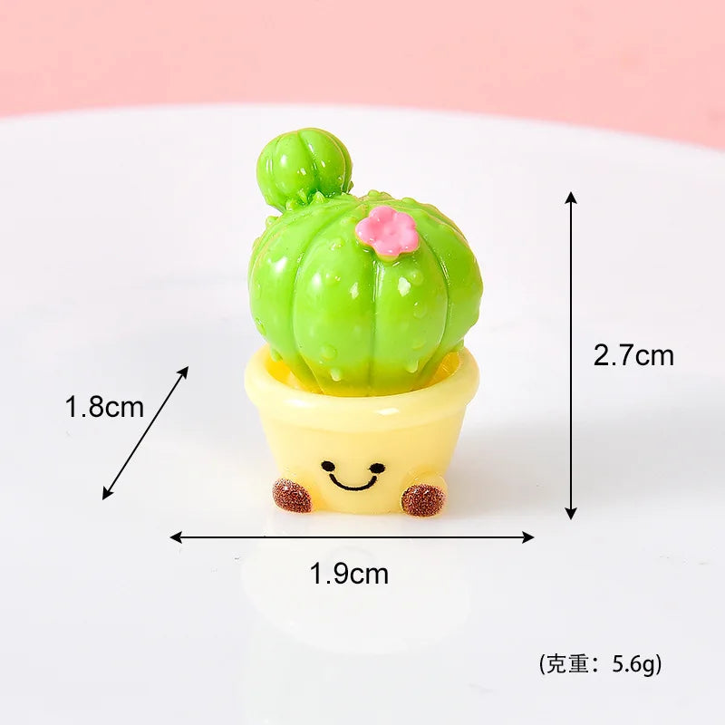 A small green cactus resin charm with a pink flower, potted in a yellow base, shown against a white background.