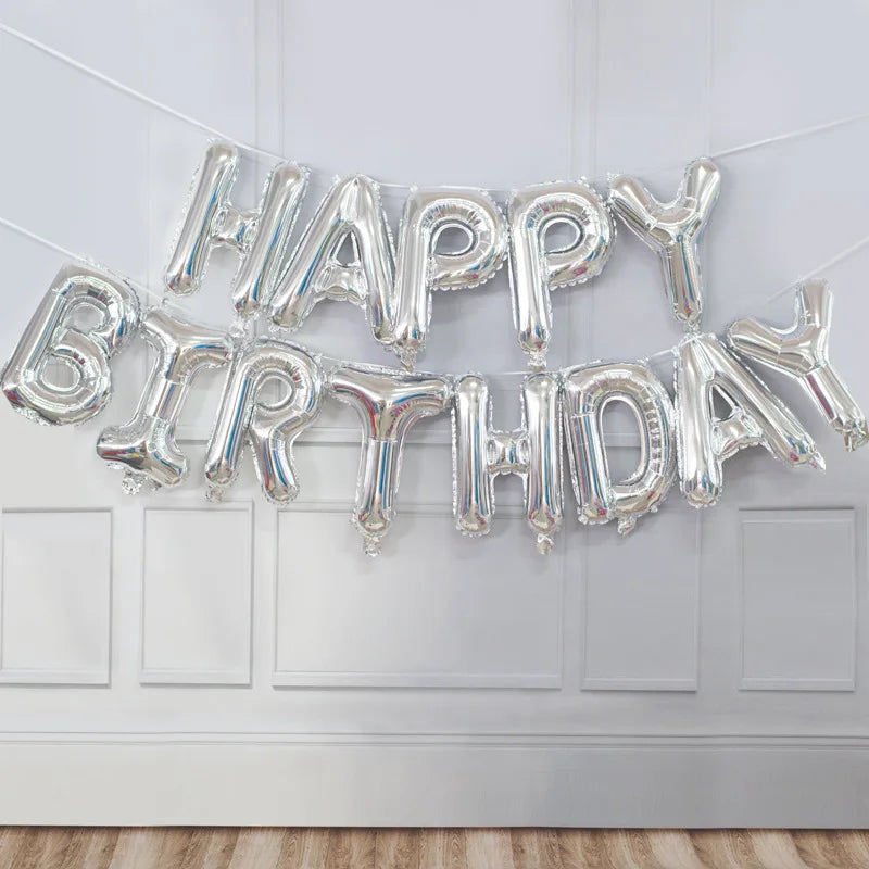 Silver foil balloon banner spelling out Happy Birthday hanging on a white door