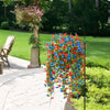 A hanging display of vibrant red, blue, and orange faux silk flowers in a garden setting.