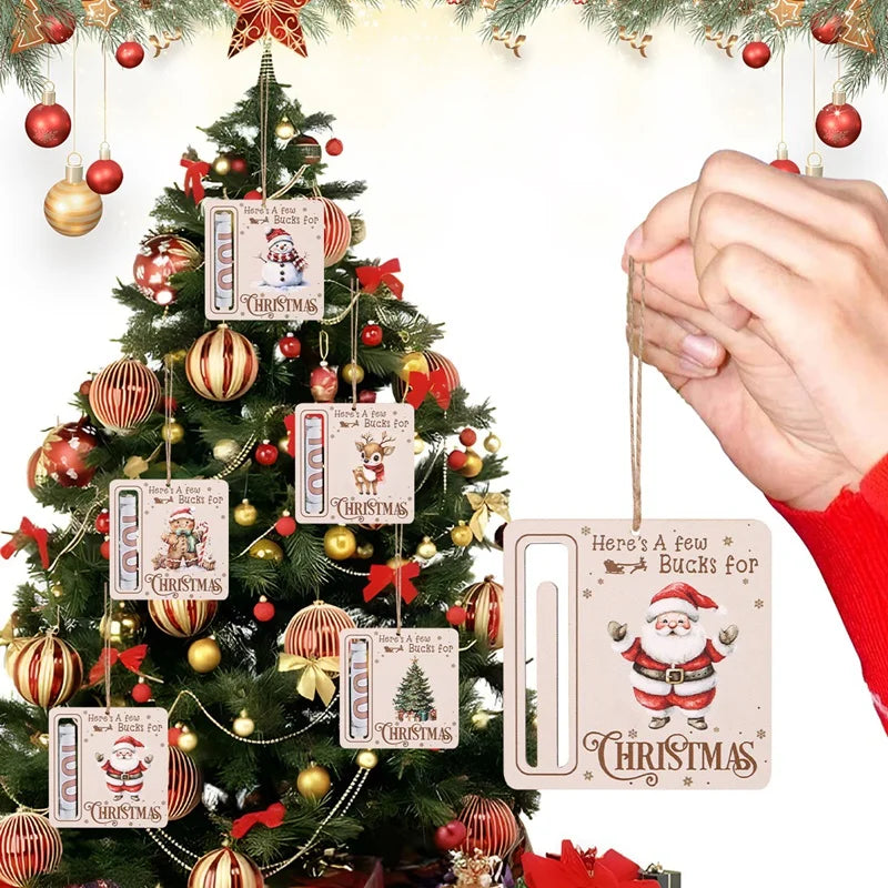 Carte monétaire en bois avec un design de Père Noël et du texte de Noël suspendue à un sapin décoré.