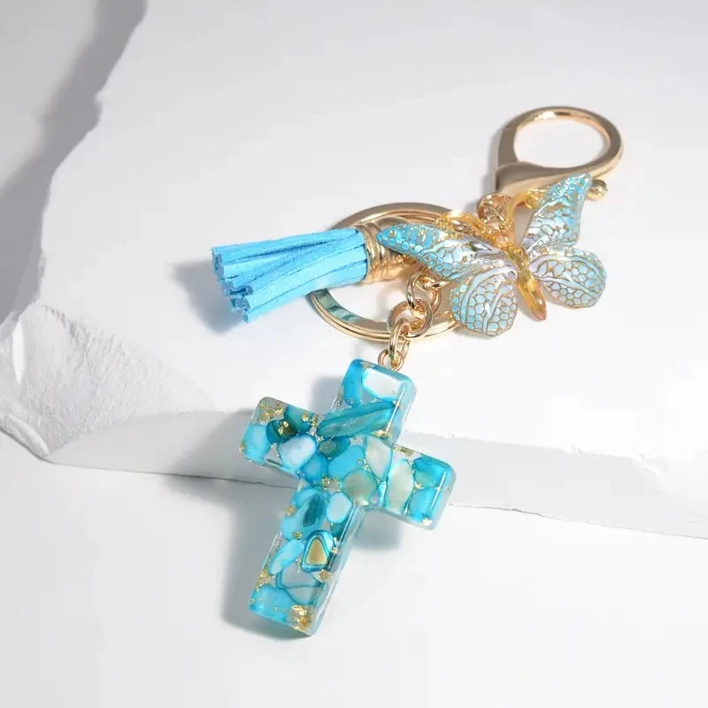 Gold-toned butterfly keychain featuring blue resin wings and a turquoise cross charm