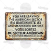 A vintage, rusted metal tin sign with text in English, Russian, and French announcing leaving the American sector.