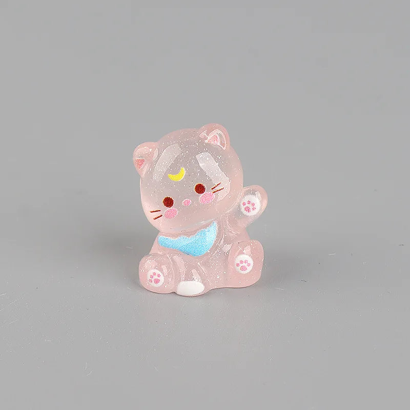 A small, pink, translucent resin cat keychain with a blue accent, featuring glitter and facial details.
