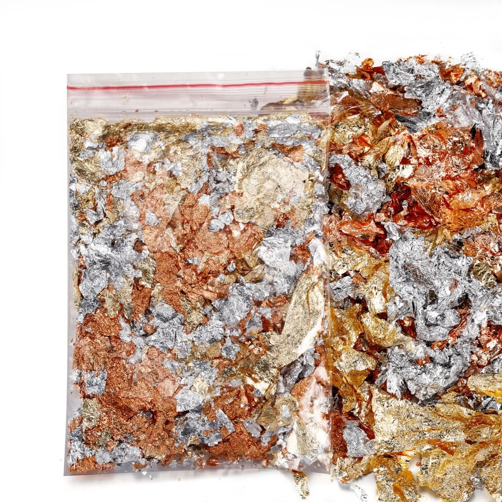 A close-up view of shiny gold foil flakes mixed with silver and copper flakes for resin art and jewelry making