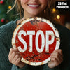 A woman holds a vintage metal round stop sign with red and white paint on it.