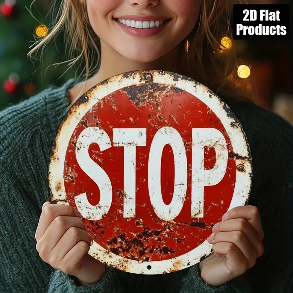 A woman holds a vintage metal round stop sign with red and white paint on it.