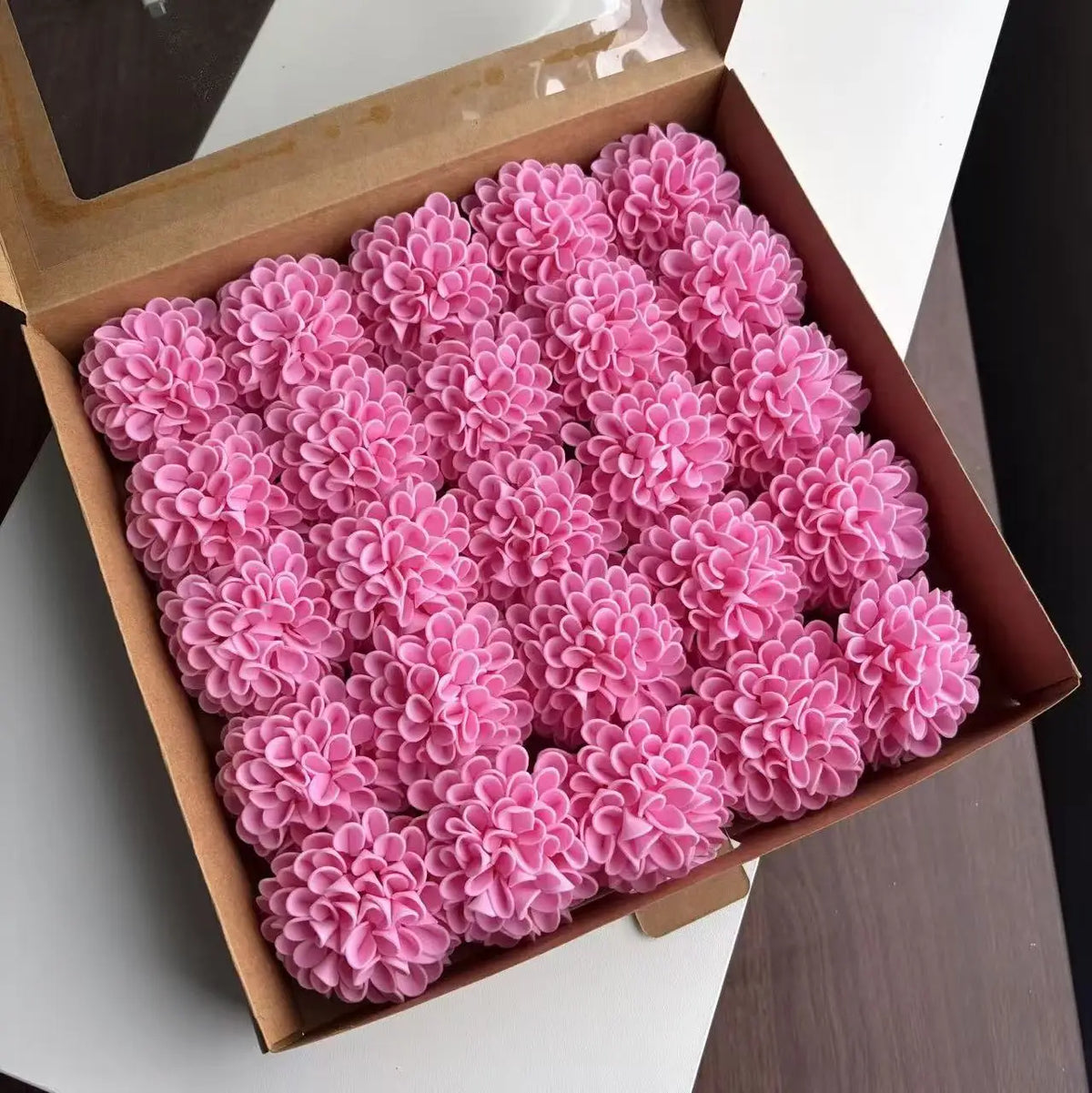 A box filled with pink lifelike foam roses for wedding and home décor