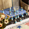 A collection of mini Virgin Mary resin statues in various colors displayed on a book with religious text.