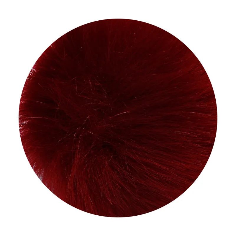 A round pom pom made of deep burgundy faux fur with a silver chain attached.