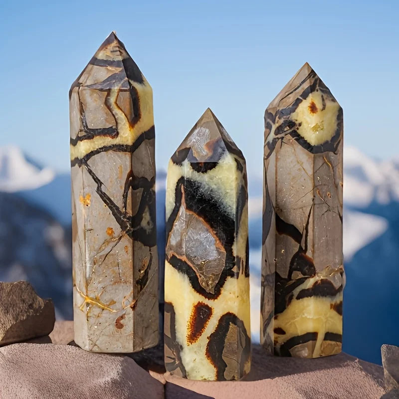 Trois points de cristal naturels de différentes tailles et couleurs, présentés sur une pierre.