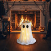 An adjustable glowing ghost lantern shaped like a sheet of white fabric sits on a wooden floor in front of a fireplace decora