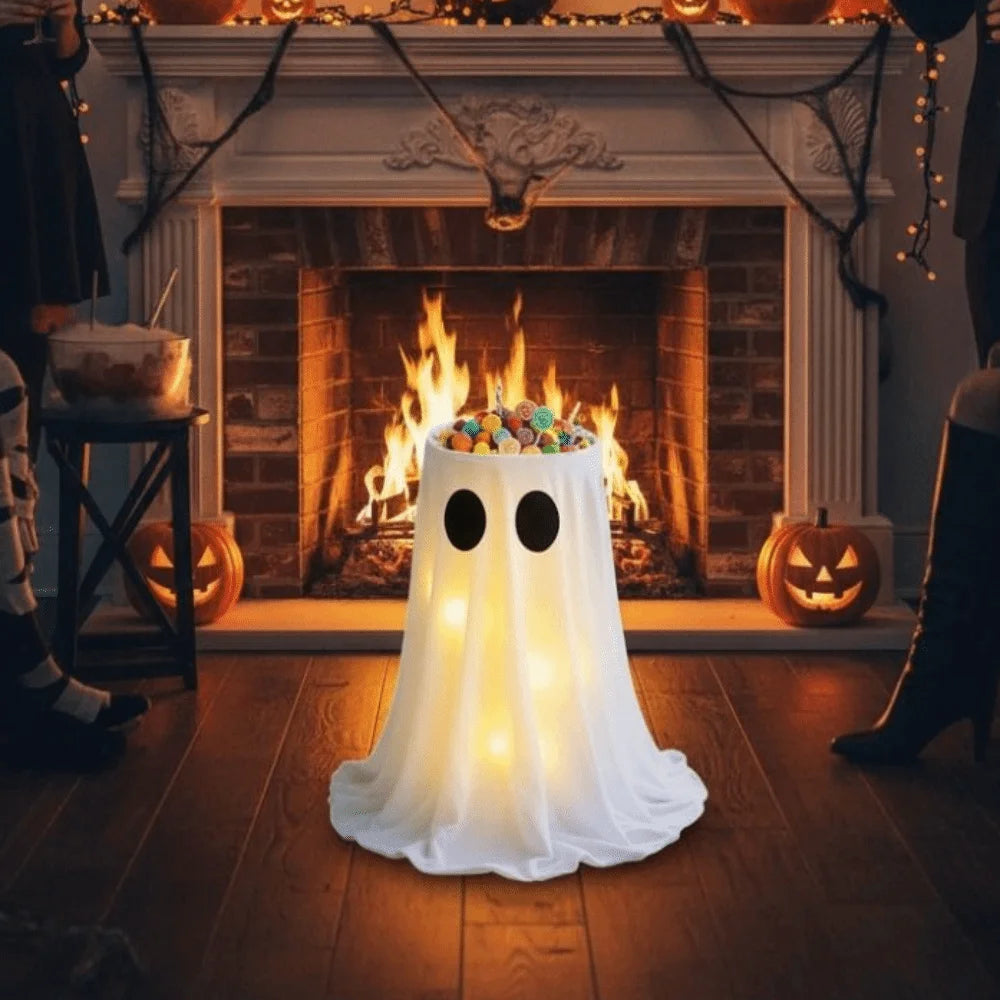 An adjustable glowing ghost lantern shaped like a sheet of white fabric sits on a wooden floor in front of a fireplace decora