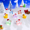 A collection of glow-in-the-dark Christmas duck figurines wearing Santa hats scattered on a snowy surface.